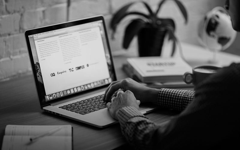 Hands typing on a laptop at a desk, a notebook and coffee cup alongside.