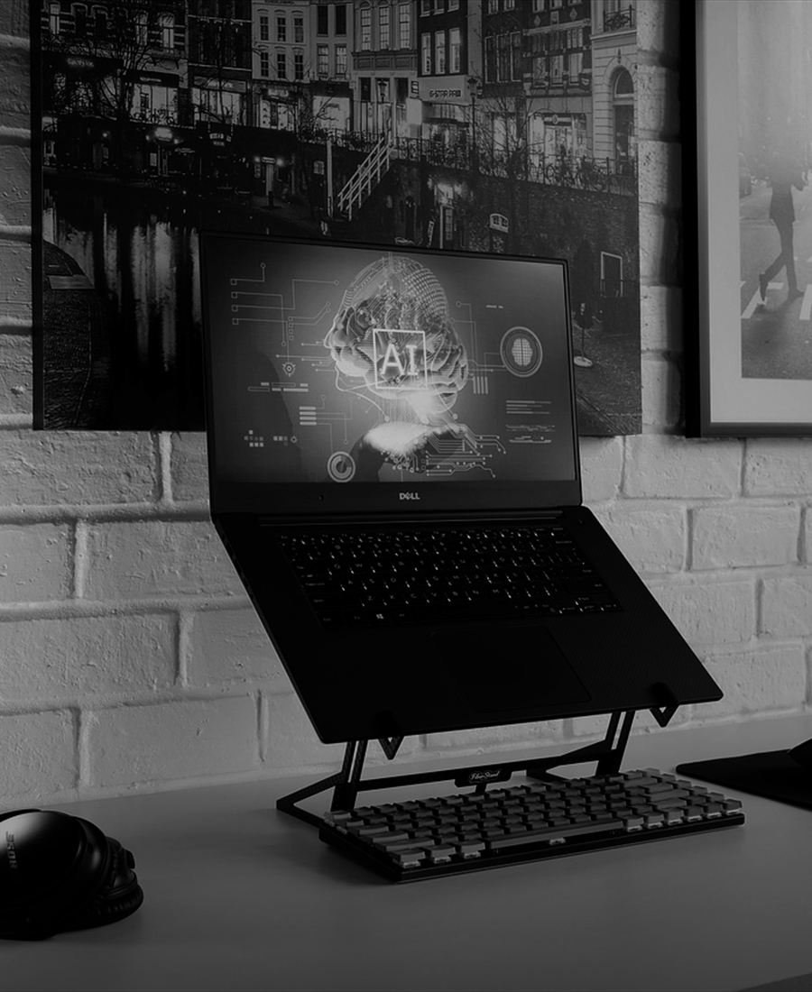 A workstation: a laptop raised on a stand with a separate keyboard, against a bare brick wall.