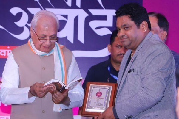 Rohit Jain receiving the framed Braj Ratna certificate from a dignitary on stage.