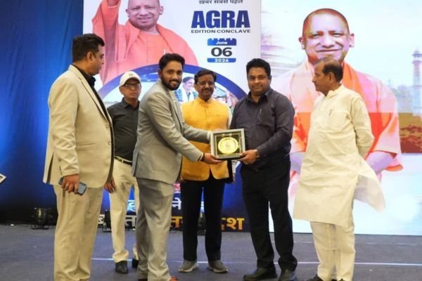 Rohit Jain among a group on stage holding a plaque at the Badhta Uttar Pradesh conclave in Agra.