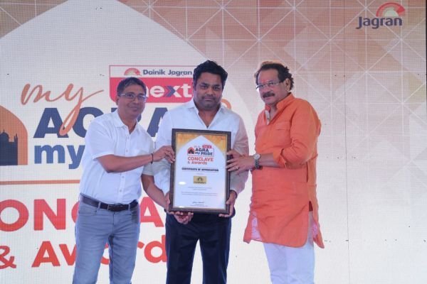 Rohit Jain holding a framed certificate in front of a my Agra my Pride backdrop.