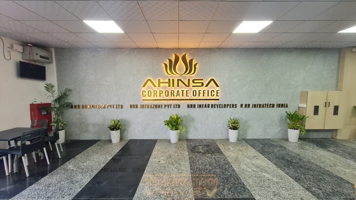 The reception of the Ahinsa corporate office, the company name lit on the wall above a polished stone floor.