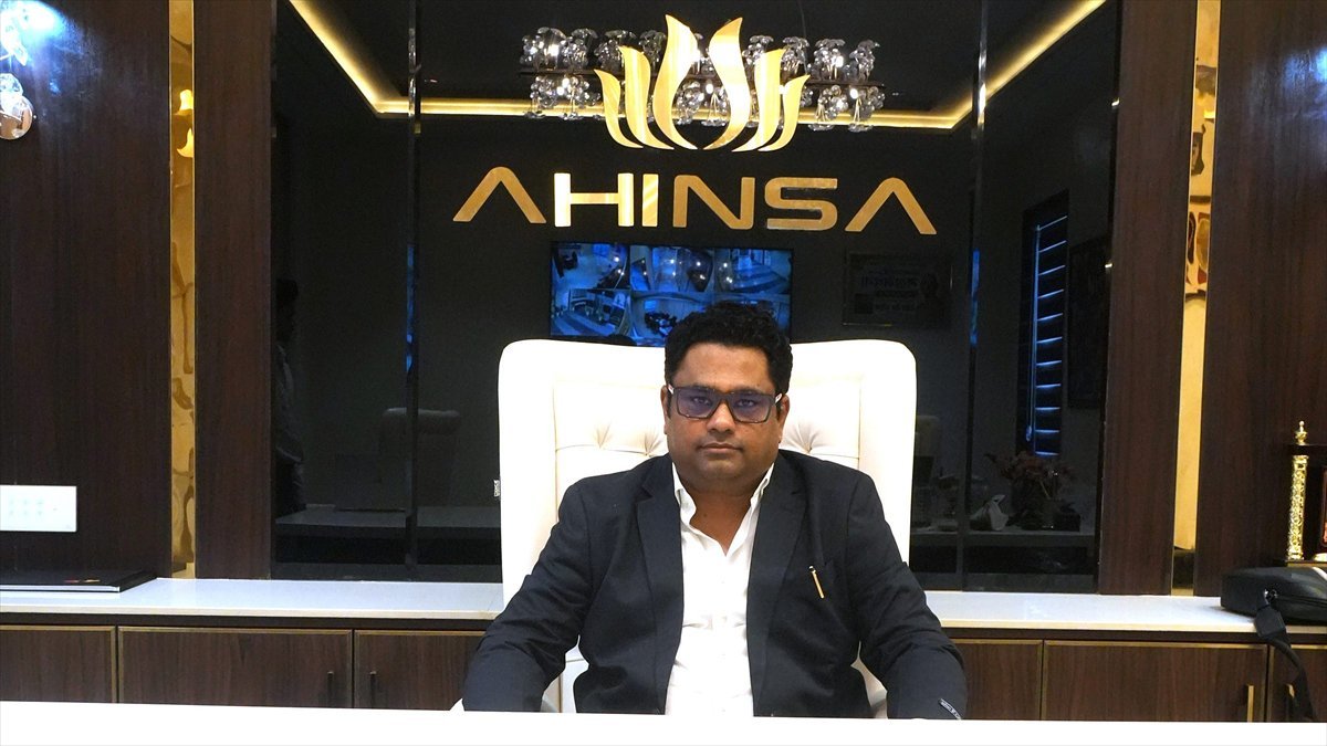 Rohit Jain seated at his desk at the Ahinsa corporate office, the company name lit on the wall behind him.