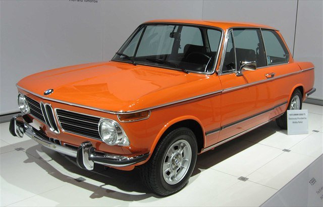 An orange 1972 BMW 2002 two-door saloon on display at the New York Auto Show.
