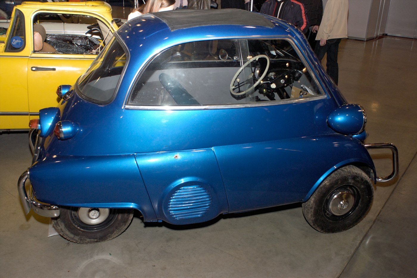A small blue BMW Isetta bubble car on display at a vintage car show.