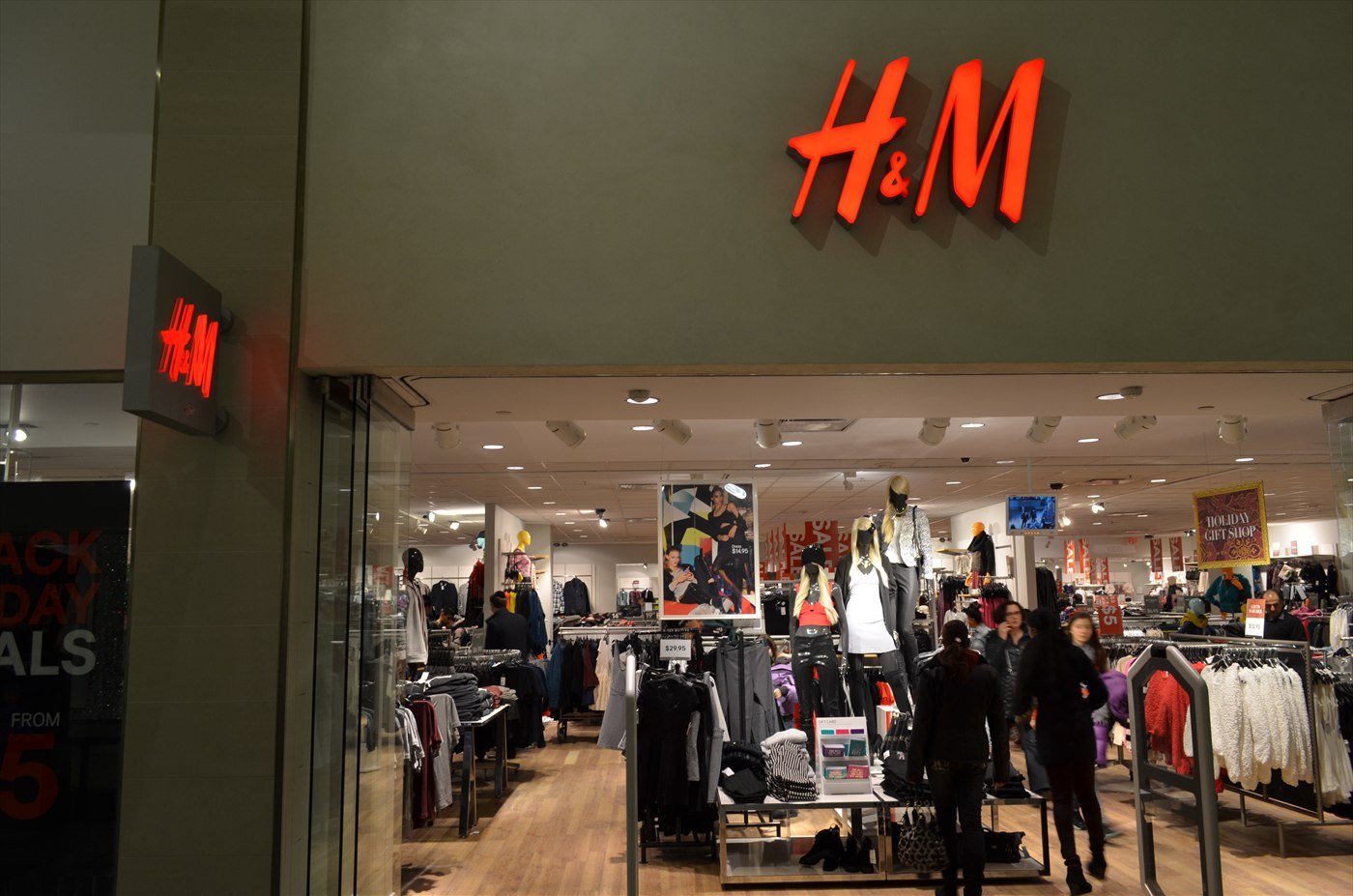 Inside an H&M store at the Vaughan Mills shopping centre in Ontario, with the red H&M logo above racks of clothing and shoppers.