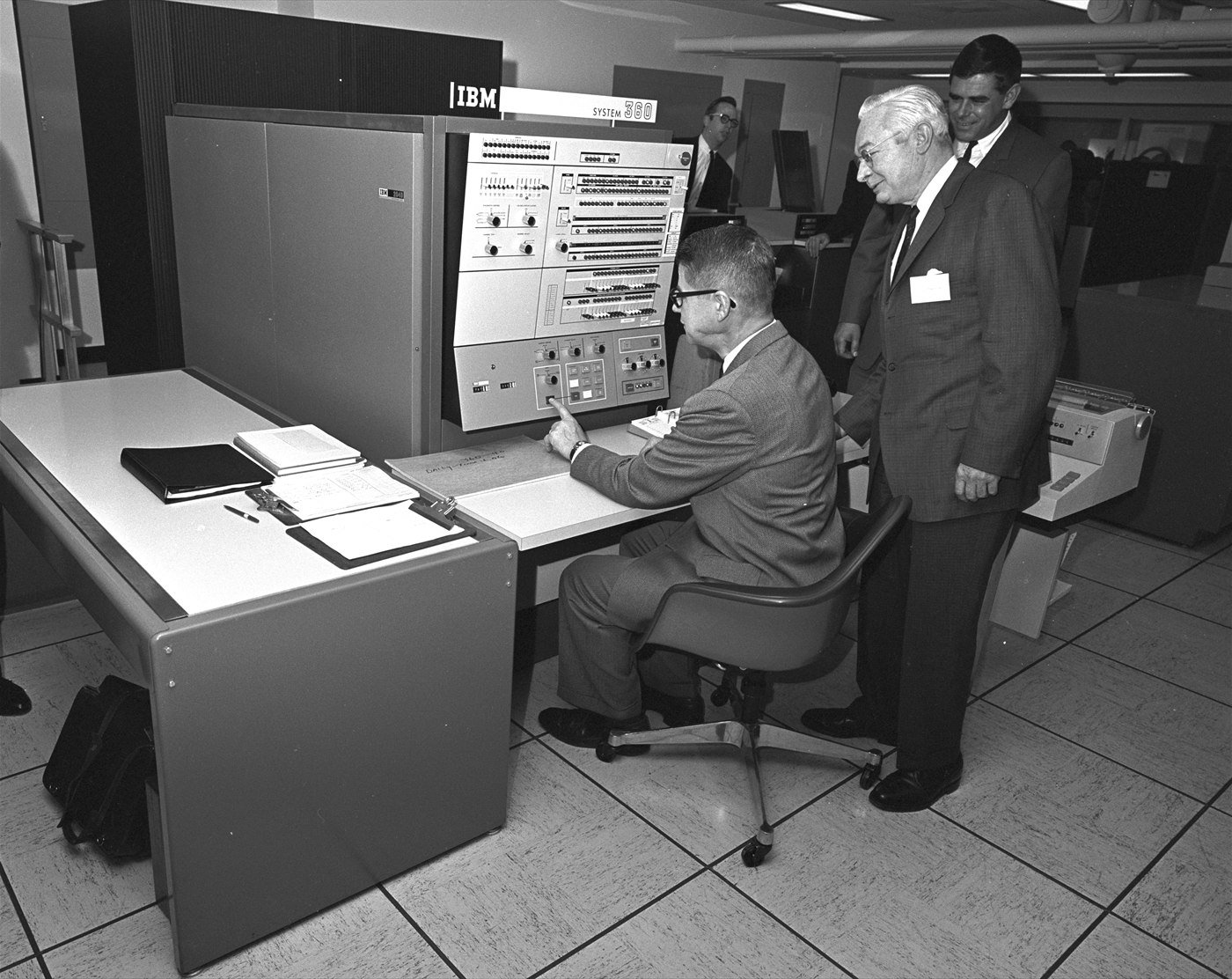 US Agriculture Secretary Orville Freeman seated at the console of an IBM System/360 while officials in suits look on, 1966.