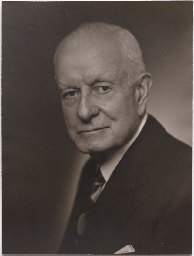 Thomas J. Watson Sr. in a formal black-and-white portrait, grey-haired and wearing a dark suit.