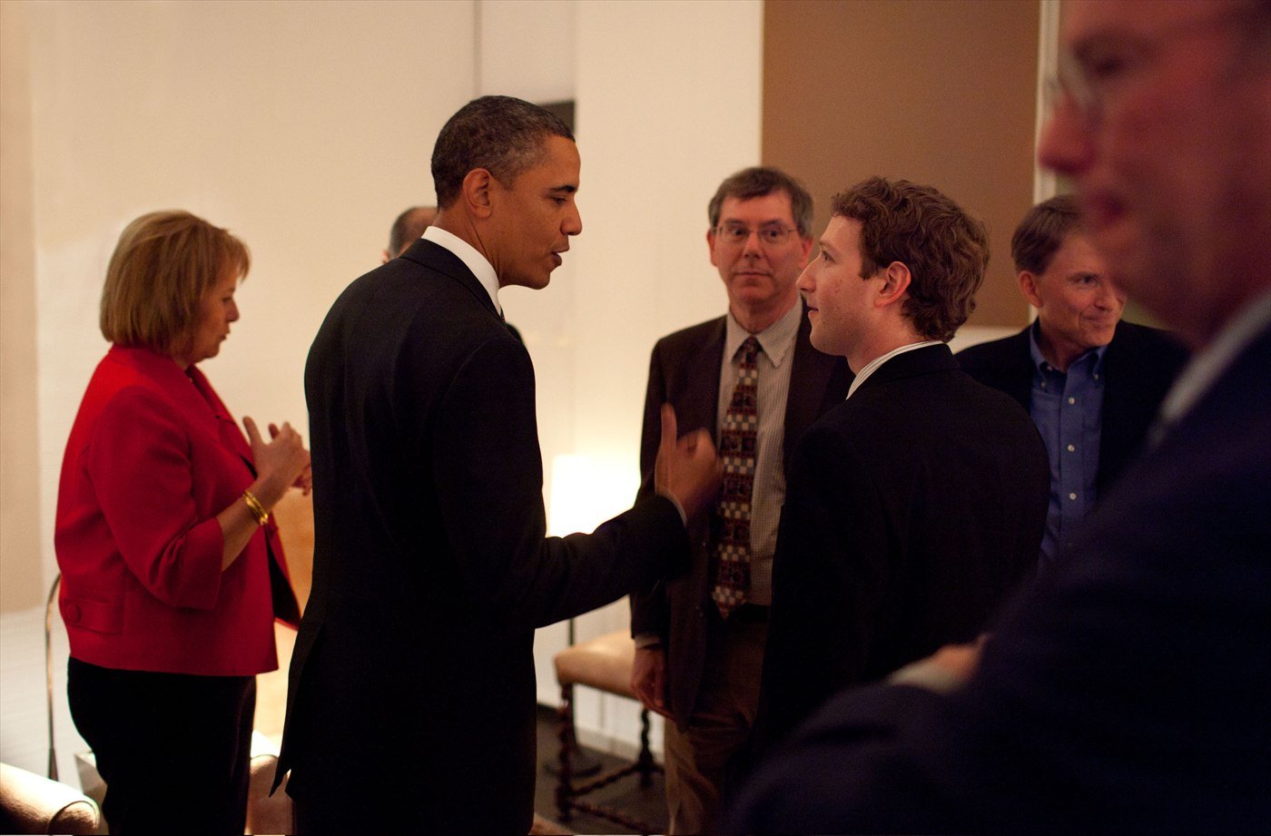Barack Obama talking with Mark Zuckerberg before a private dinner with technology executives, other guests standing around them.