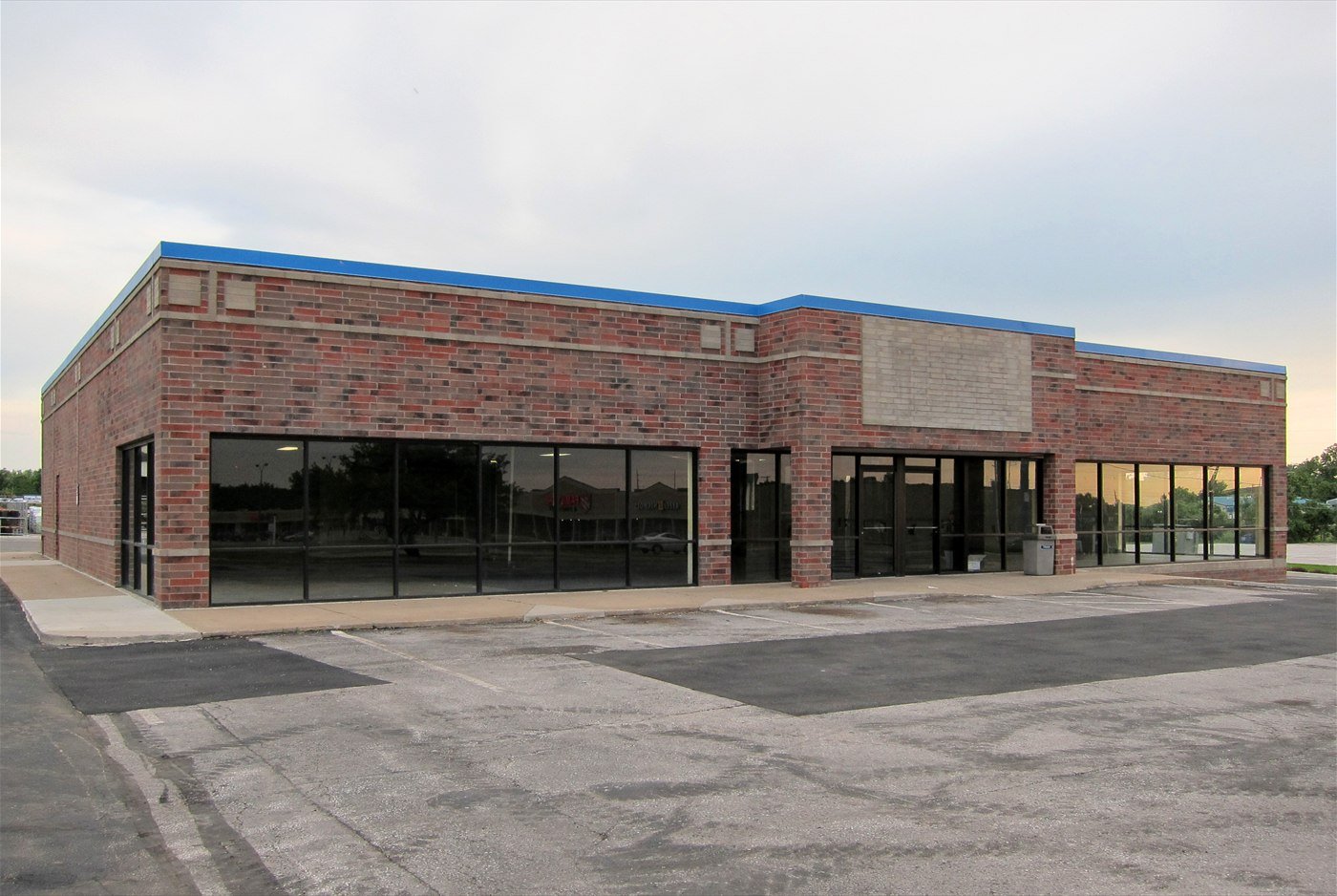 An empty, closed Blockbuster video-rental store building with bare windows and an empty car park.