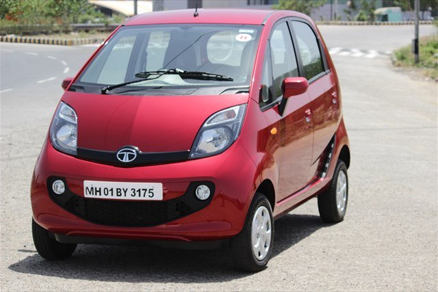 A red Tata Nano GenX hatchback parked on a road.