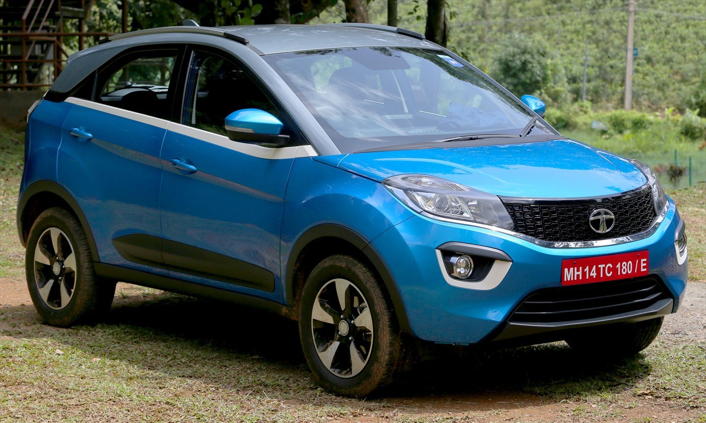 A blue Tata Nexon compact SUV with a white roof parked beside a road.