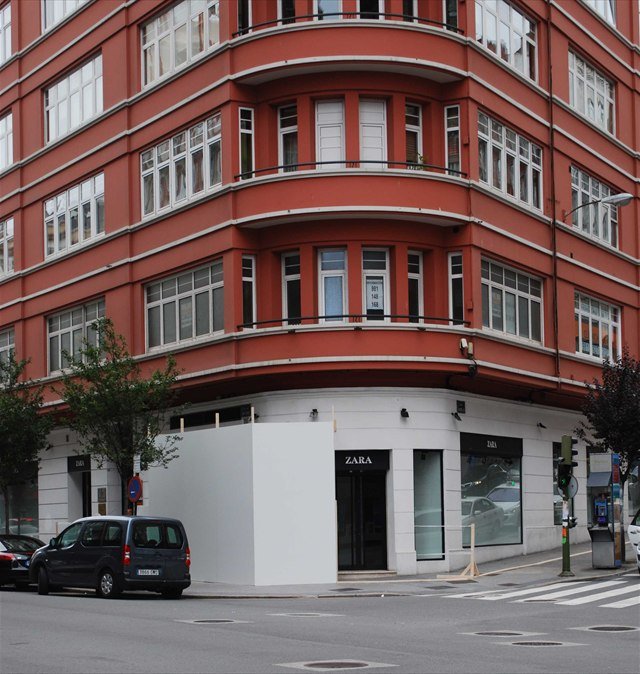 A red-brick corner building in A Coruña with a shopfront at street level.
