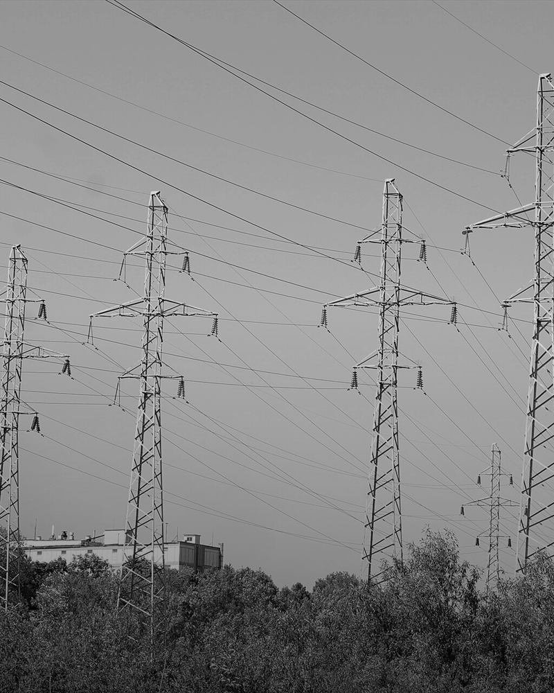 A line of high-voltage transmission towers against an open sky.