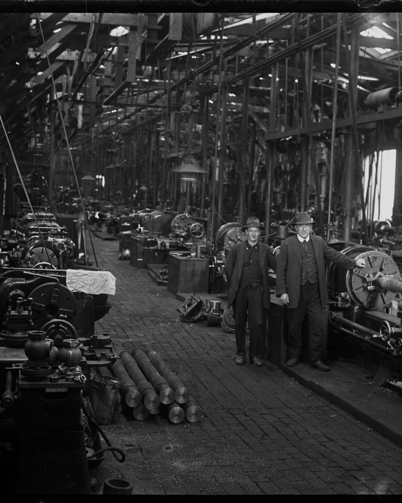 Machinists among lathes on a workshop floor.